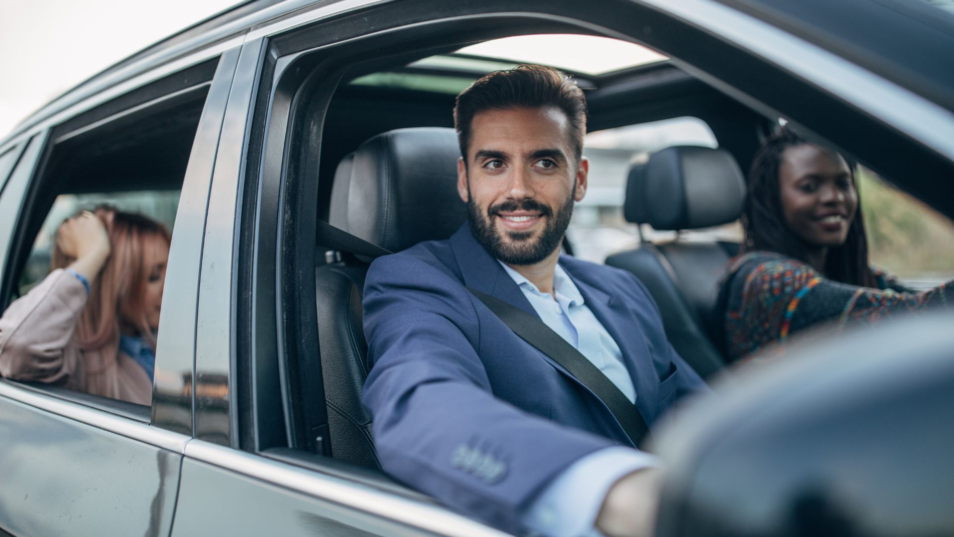 A man in a suit sitting in the passenger seat of a car