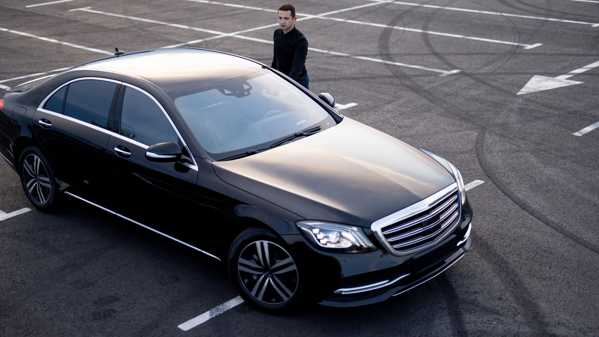 A man standing next to a black car in a parking lot